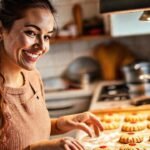 Una mujer sonríe horneando galletas en cocina
